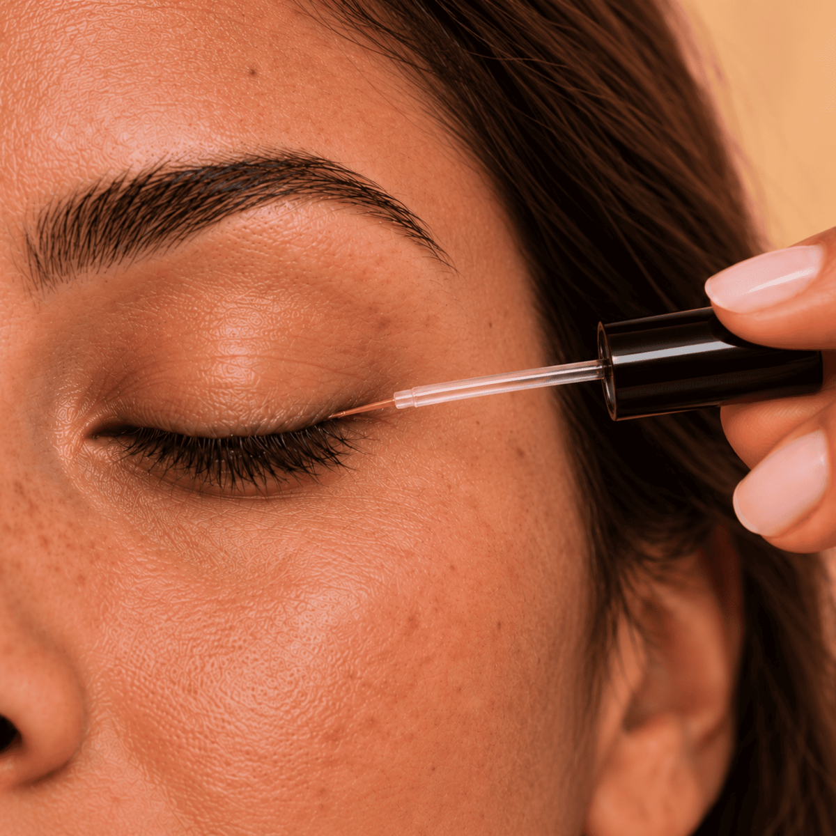 Femme appliquant de l'huile végétale de Ricin sur ses cils à l'aide d'un goupillon pour fortifier et stimuler la pousse.