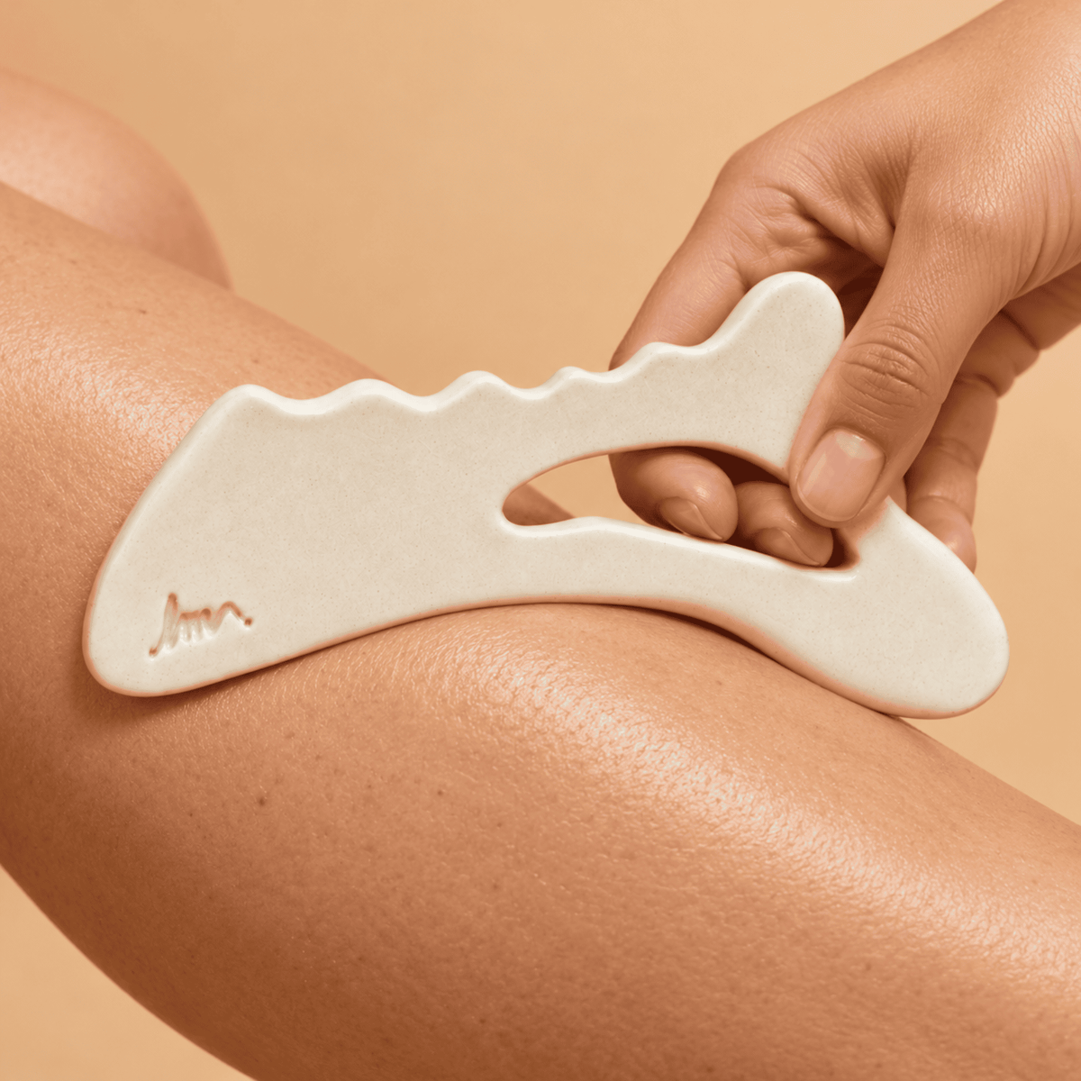Gua Sha corps en pierre naturelle posé dans un décor de salle de bain pour le massage lymphatique et le soin de la peau.