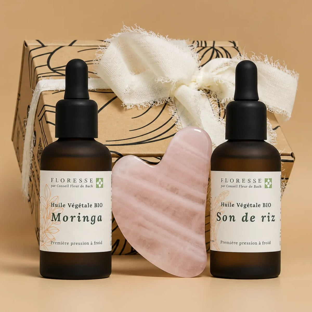 Gua Sha et duo d'huiles végétales présentés devant leur coffret cadeau.