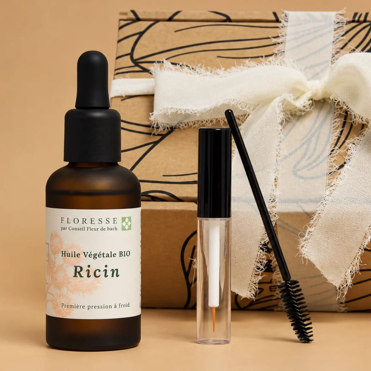 Huile de ricin et goupillon d'application présentés devant leur coffret cadeau.